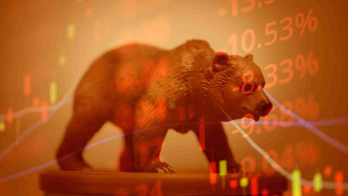 A bear figurine set against a backdrop of red-hued trading charts and stock prices