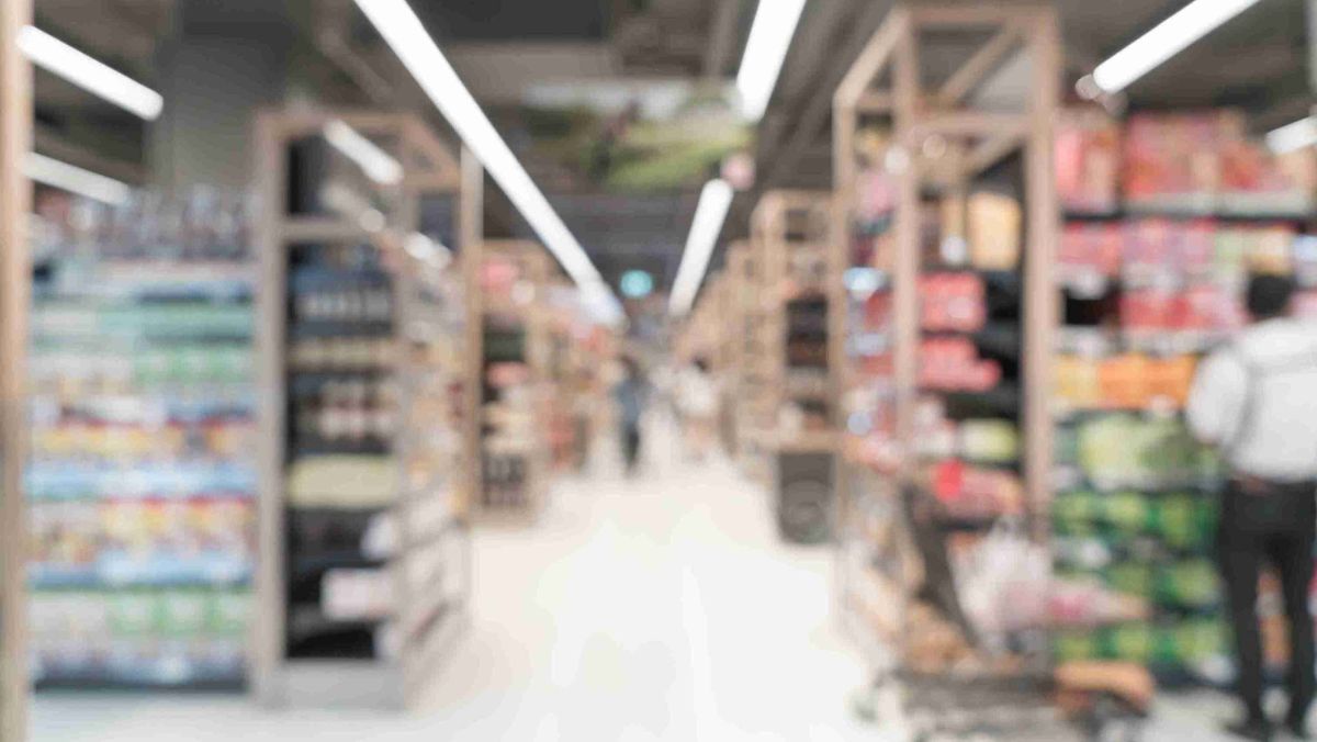 A blurred perspective of a supermarket featuring shelves stocked with various products