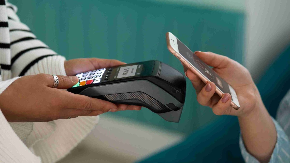 A consumer using a mobile phone for payment with the merchant confirming the transaction through a detector
