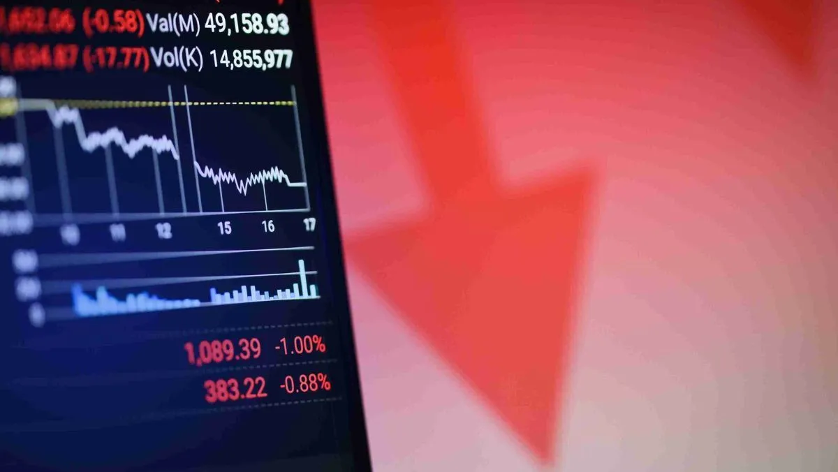 A declining stock market data is displayed on a screen, and a huge red downward arrow behind