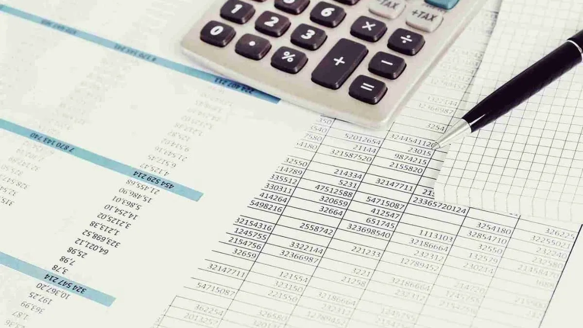 A document packed with multiple numerical values, a calculator, and a pen