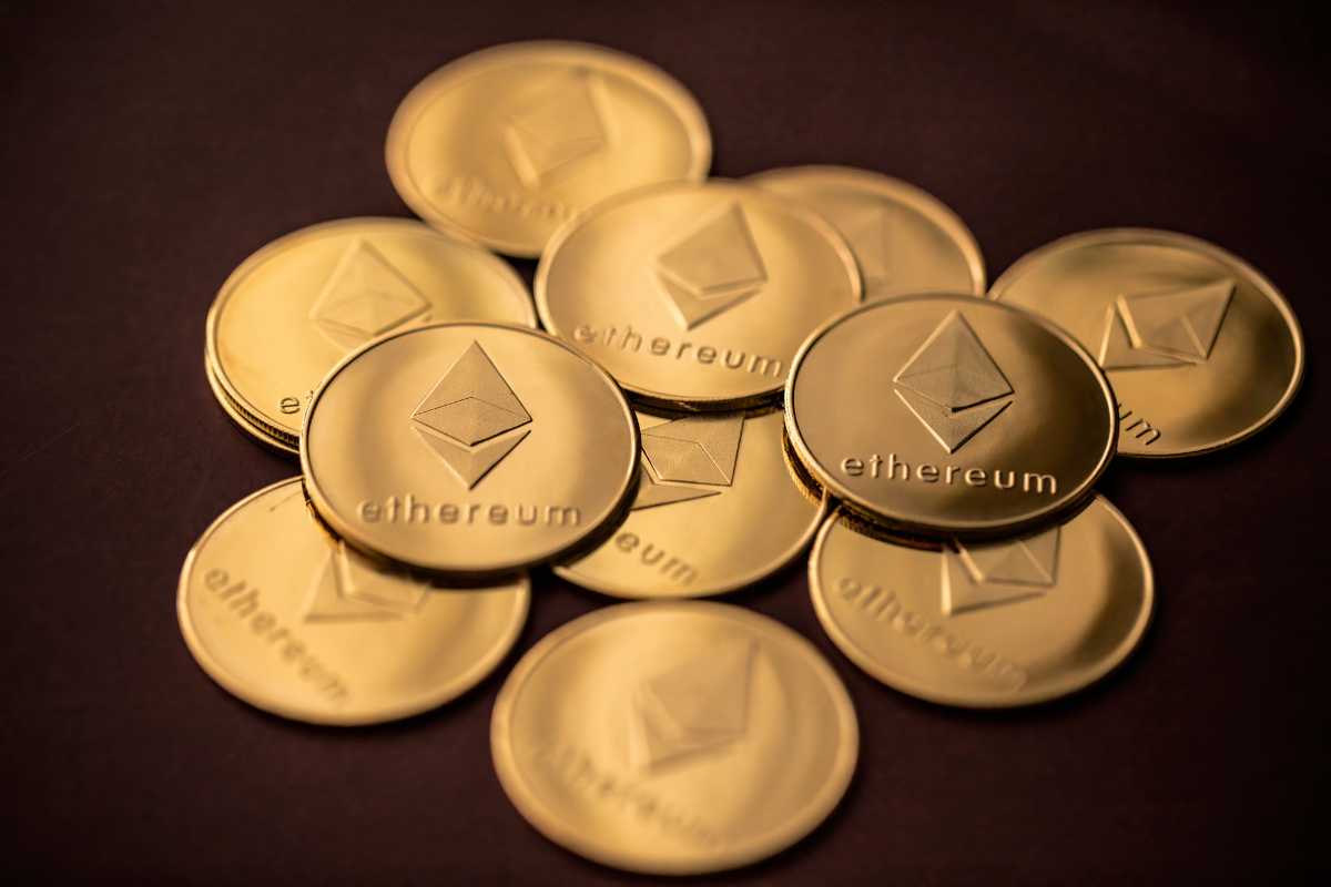 A golden Ethereum coin in sharp focus against a blurred background of various other cryptocurrency coins