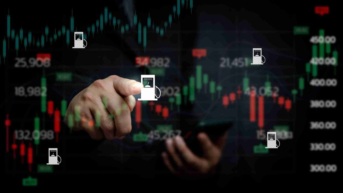 A hand directing attention to a gasoline station icon against the backdrop of a trading chart