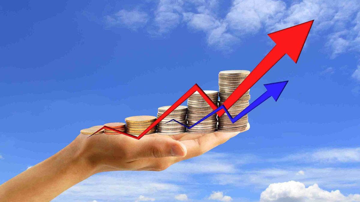 A hand holding a stack of coins, accompanied by upward-pointing red and blue arrows