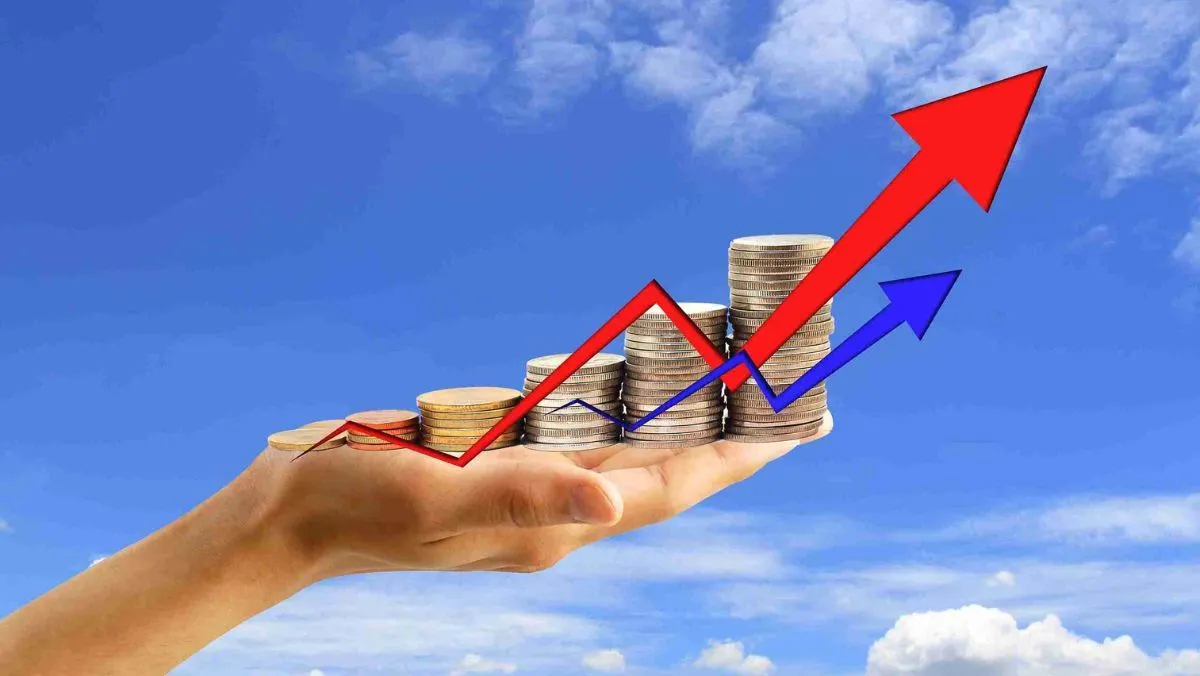 A hand holding a stack of coins, accompanied by upward-pointing red and blue arrows
