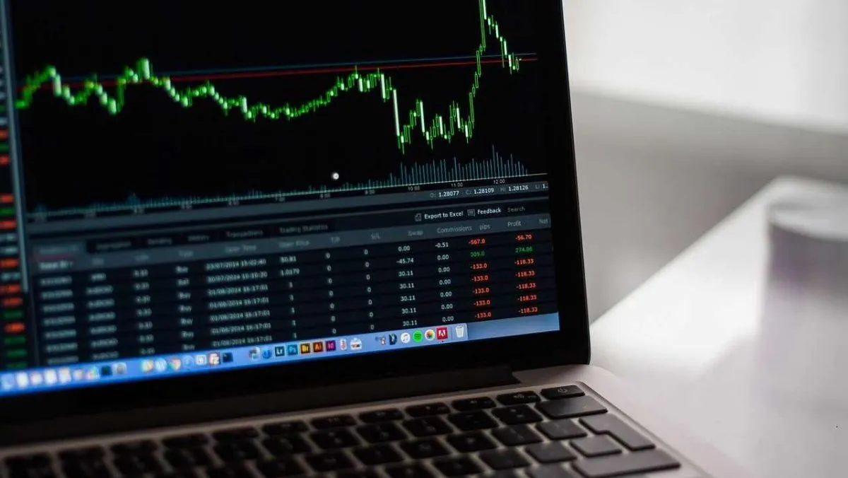 A live trading chart with green candlestick patterns displayed on a laptop