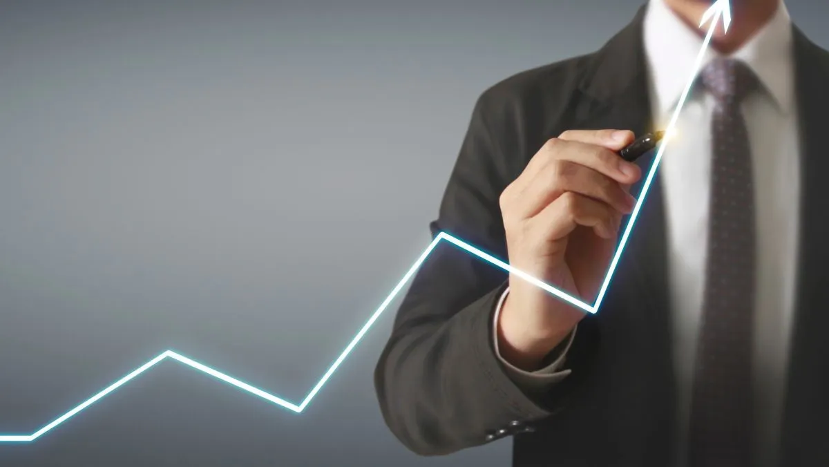A man in formal attire pointing an upward direction of a white arrow using a pen 