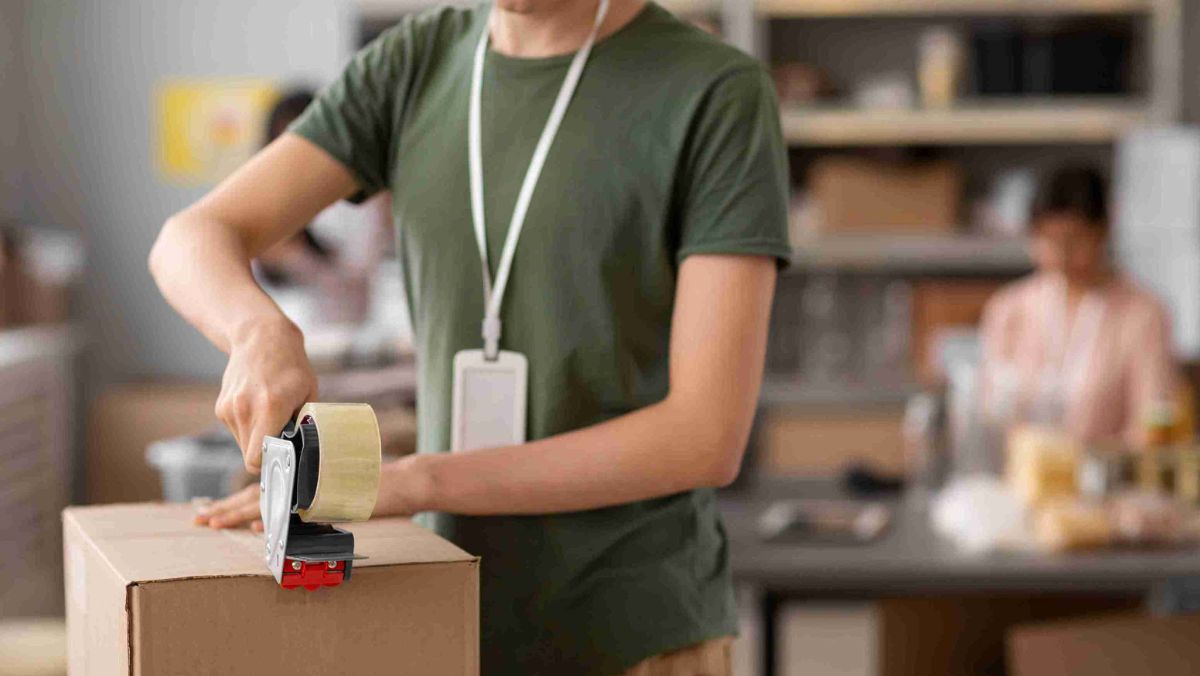 A man is affixing a tape to a box for secure handling