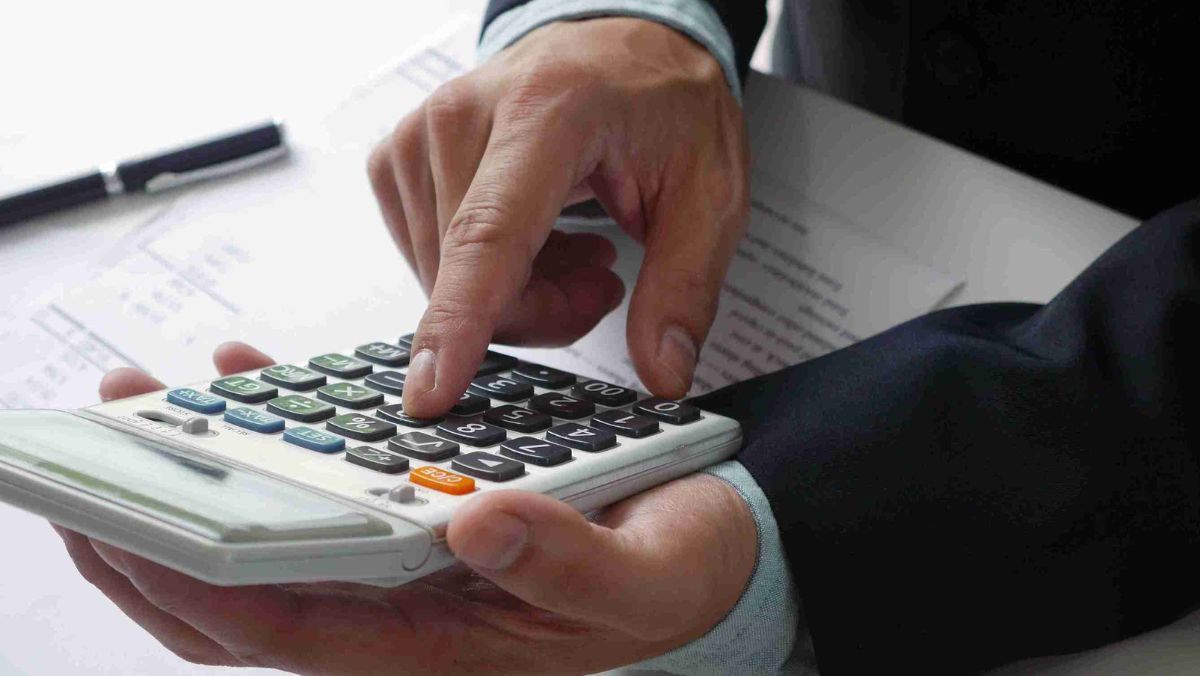A man using a calculator on his desk with papers on the table