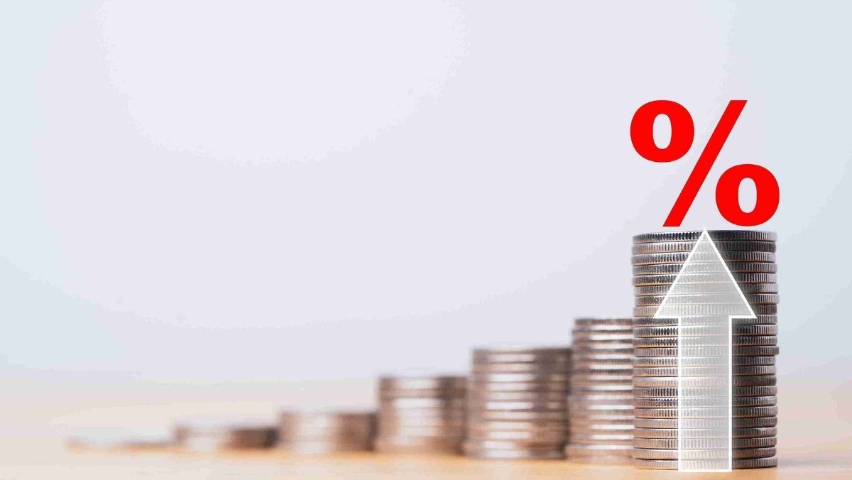 A neatly organized stack of coins accompanied by an upward arrow featuring a red percentage symbol