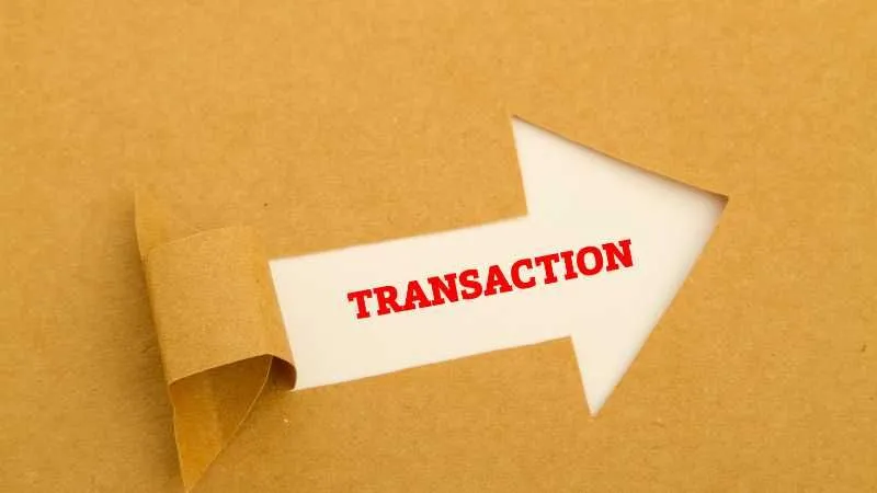 A paper arrow on a brown background with the word TRANSACTION  on it