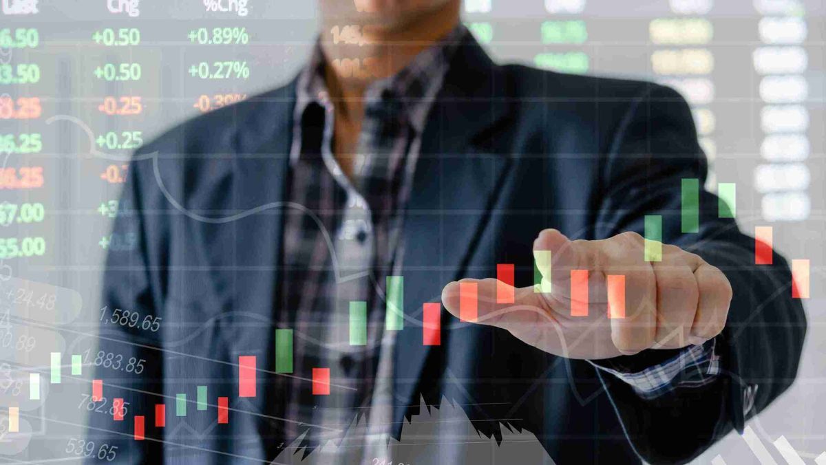 A person gesturing toward a trading pattern set against the backdrop of stock market data