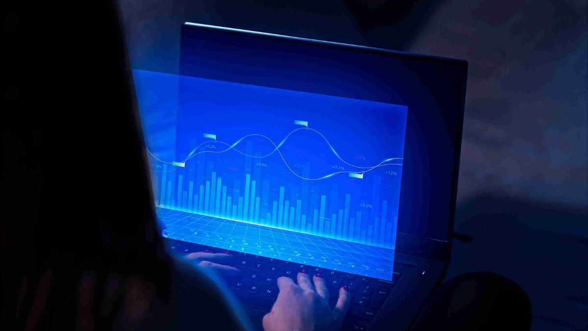 A person presenting a lively scene of vibrant blue lines and bar graphs on a laptop screen