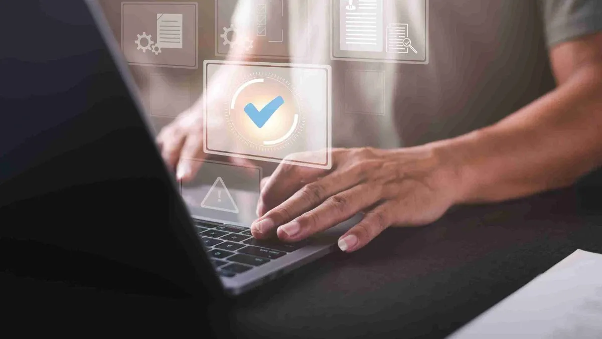A person working on a laptop, displaying a checkmark and document icons