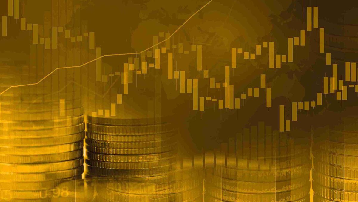 A pile of coins alongside a trading graph adorned with a golden hue.