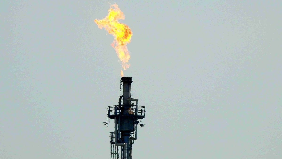 A towering oil rig engulfed in flames against the backdrop of the sky