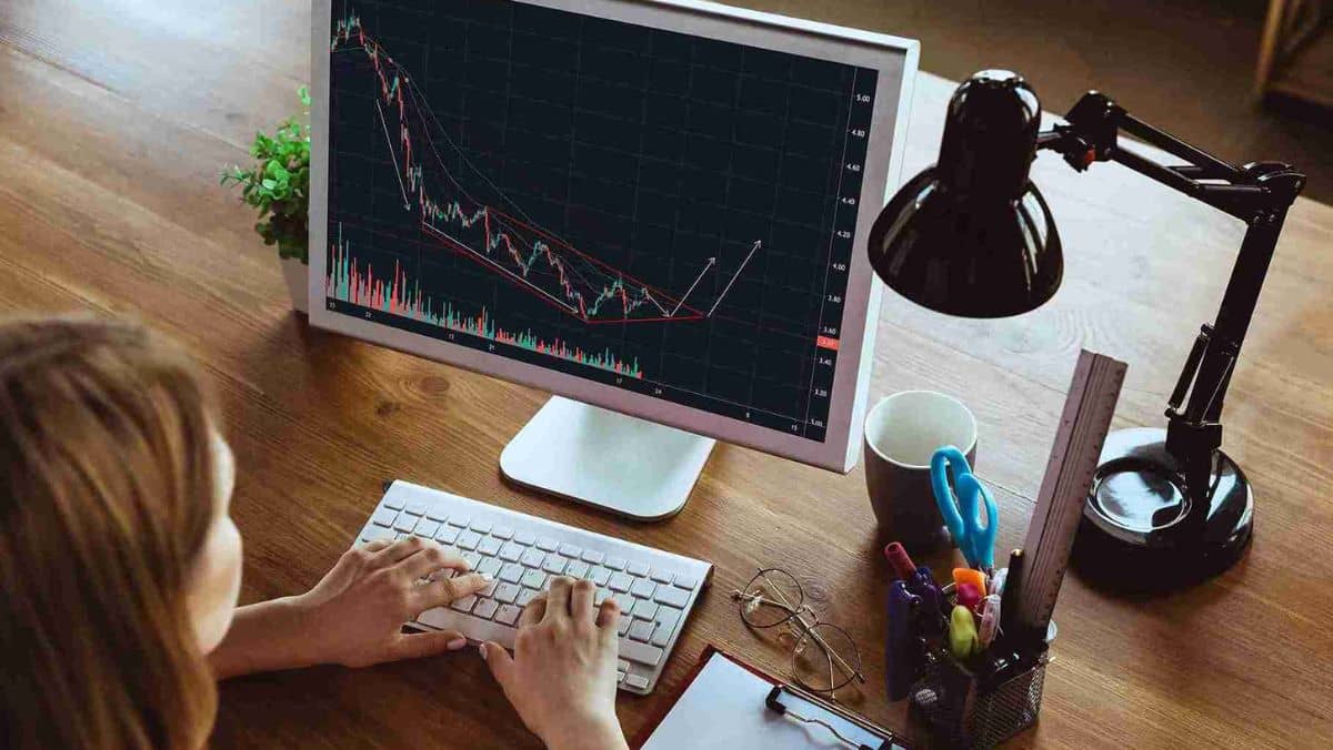 A trader at a computer observing an ascending trading pattern on the screen