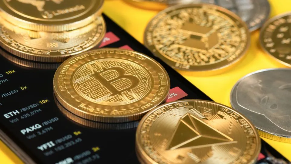 Assortment of cryptocurrency coins including Bitcoin and Ethereum on a digital screen displaying market trends and values