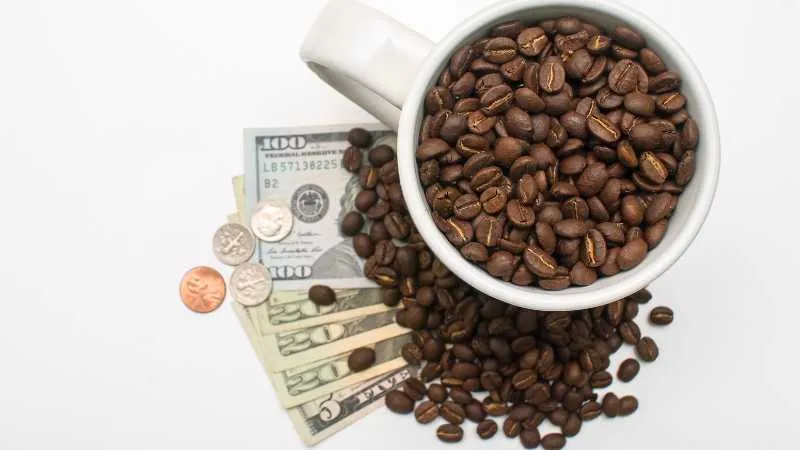 Coffee beans in a cup with US currency symbolising the value of coffee
