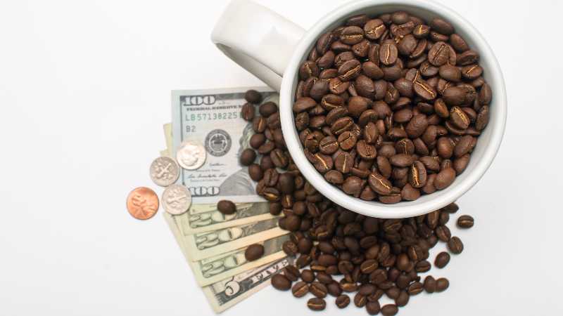 Coffee beans in a cup with US currency, symbolizing the value of coffee