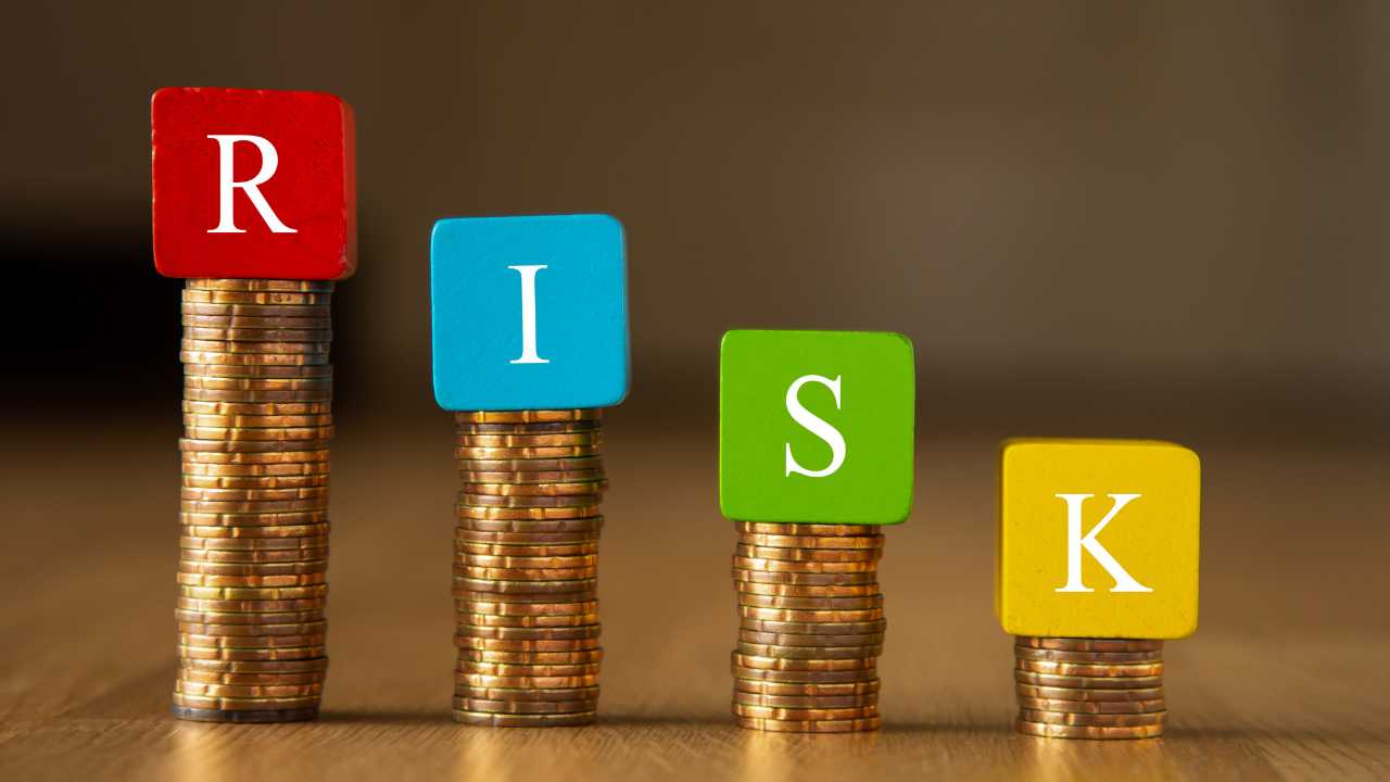 Colorful blocks spelling RISK on top of coin stacks.