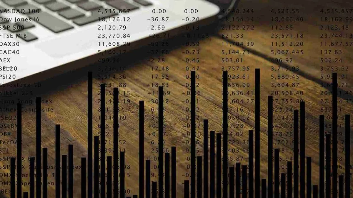 Dark hued bar graphs displaying numerical stock data alongside a laptop positioned on the table