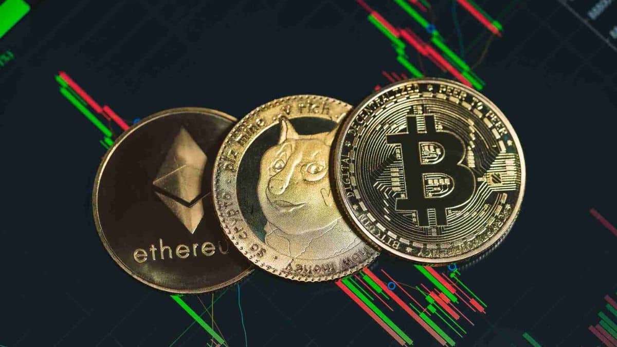 Ethereum DogeCoin and Bitcoin laid down on a digital screen displaying a candlestick chart