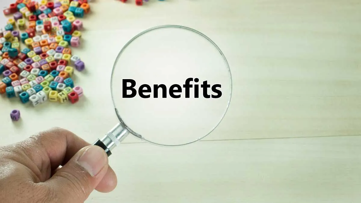Hand holding magnifying glass over the word Benefits with letter beads in background