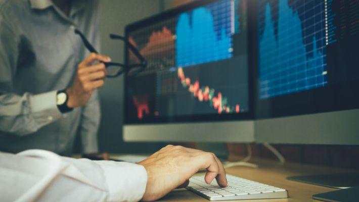 Man at the desk looking at a computer screen showing stock market trading data.jpg