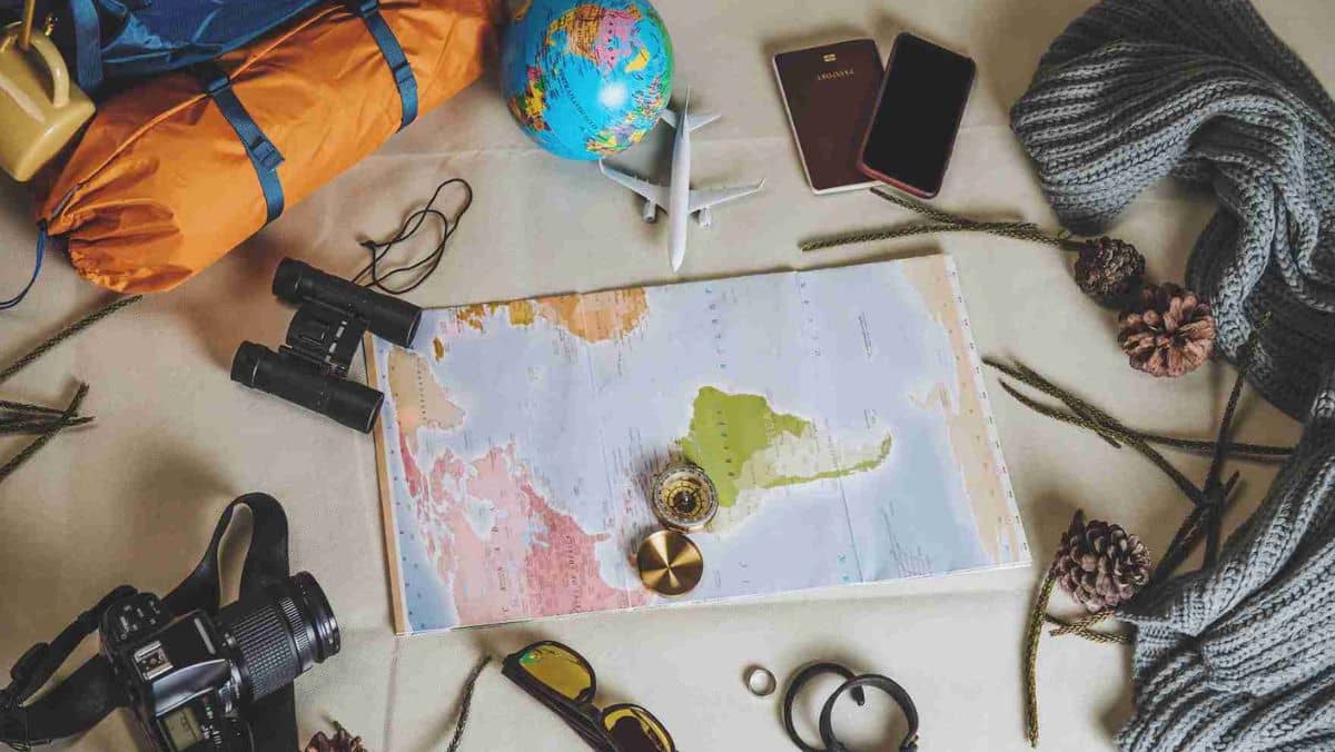 Positioned at the centre is a map encircled by holiday essentials a passport and a miniature aeroplane