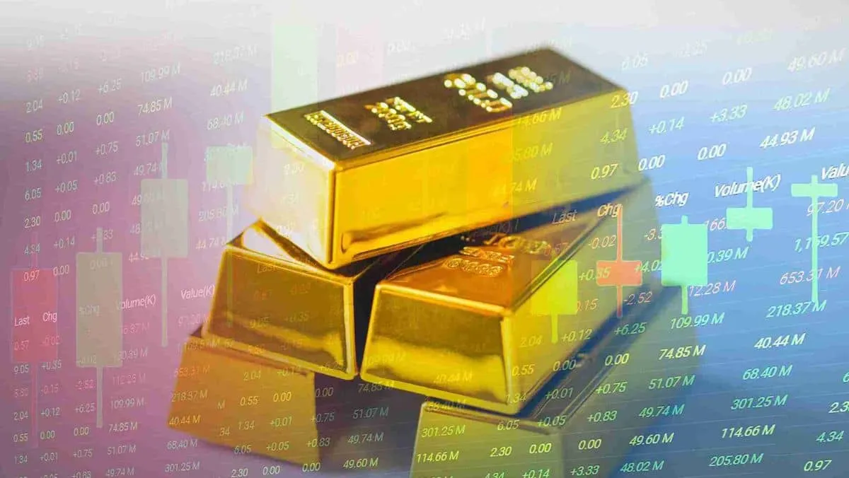 Stack of gold bars is displayed with stock market data in the background