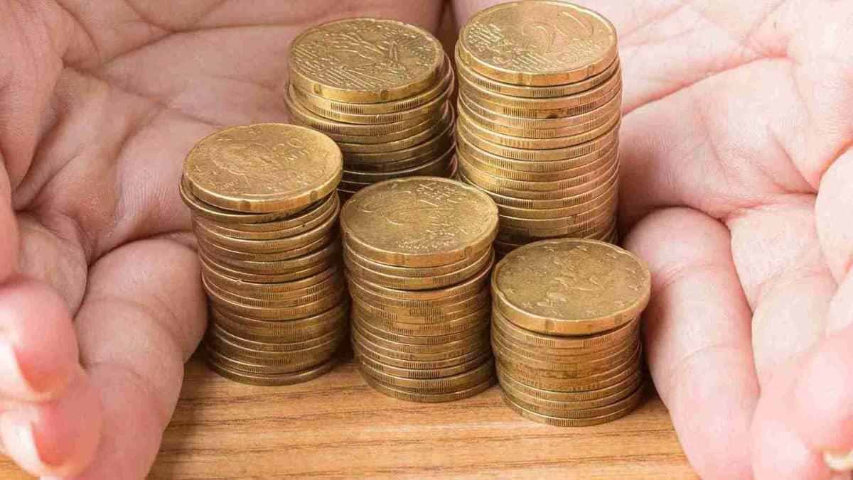 Two hands encircling a stack of gold coins forming a protective gesture