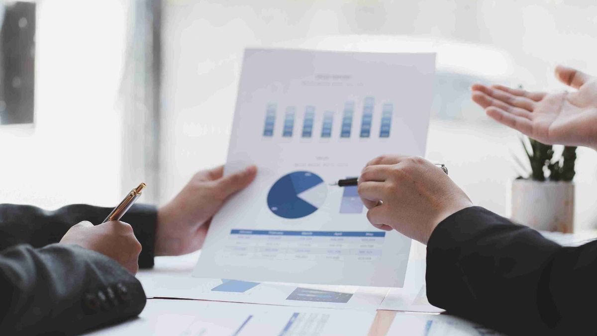Two individuals engaged in a discussion about charts depicted on a paper document