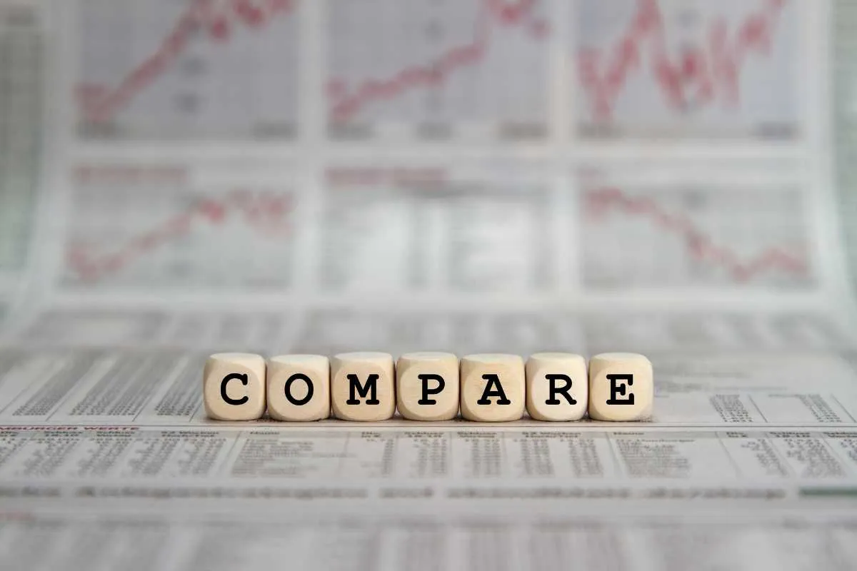 Wooden blocks spelling COMPARE  on a stock market report background