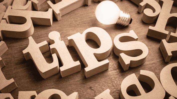 Wooden letters spelling TIPS with a glowing light bulb on a wood surface