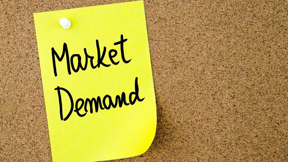 Yellow sticky note on a corkboard with Market Demand written on it