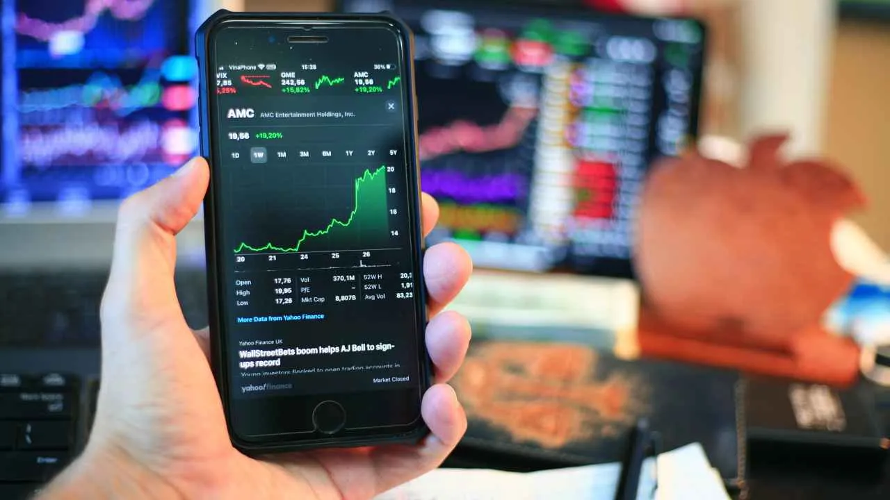 a hand holding a cell phone with a screen showing a stock market chart